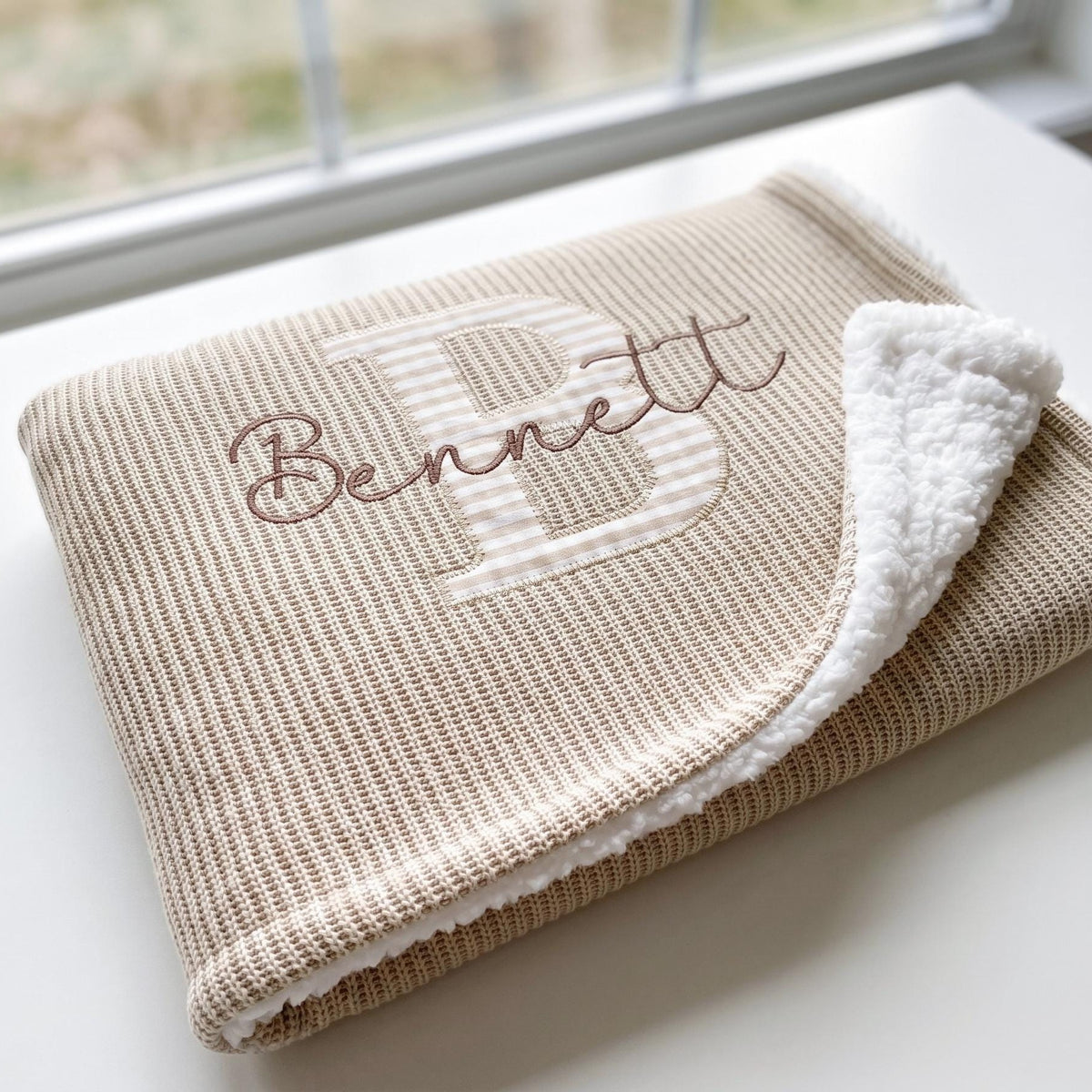 Folded beige personalized sherpa baby blanket with gingham applique letter B and embroidered name Bennett