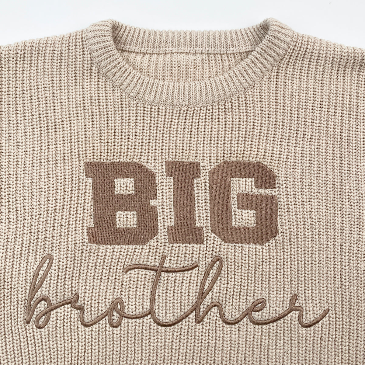 Close-up of BIG brother embroidery in taupe thread on beige cotton knit sweater