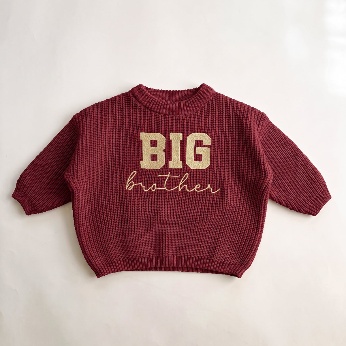 Red chunky knit baby sweater with BIG brother embroidery, laid flat