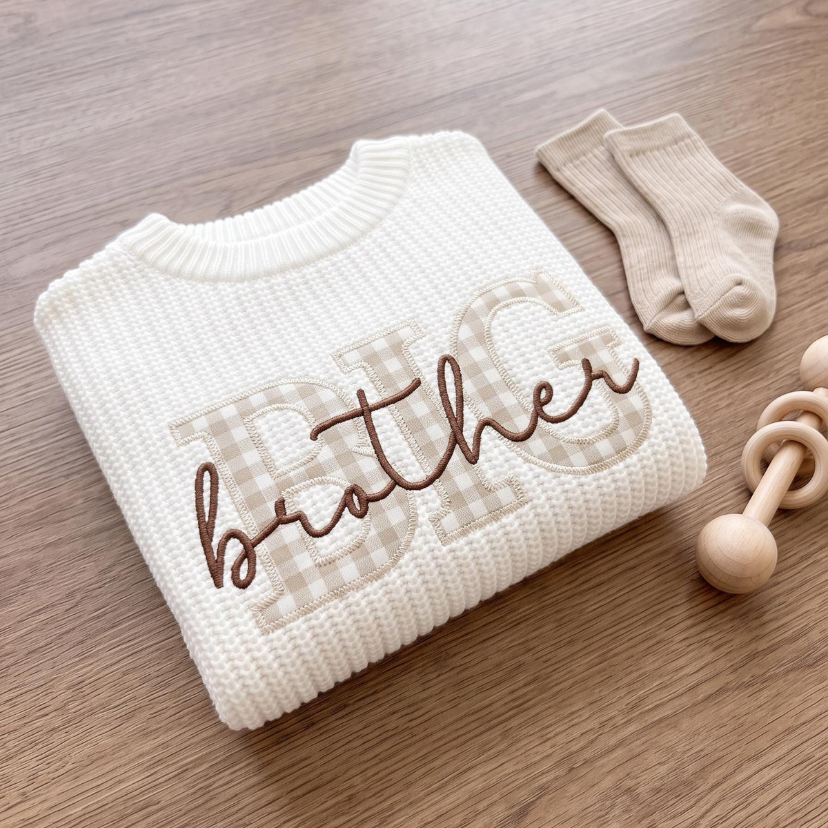 Folded white knit sweater with beige gingham BIG applique letters and brother embroidered in brown script