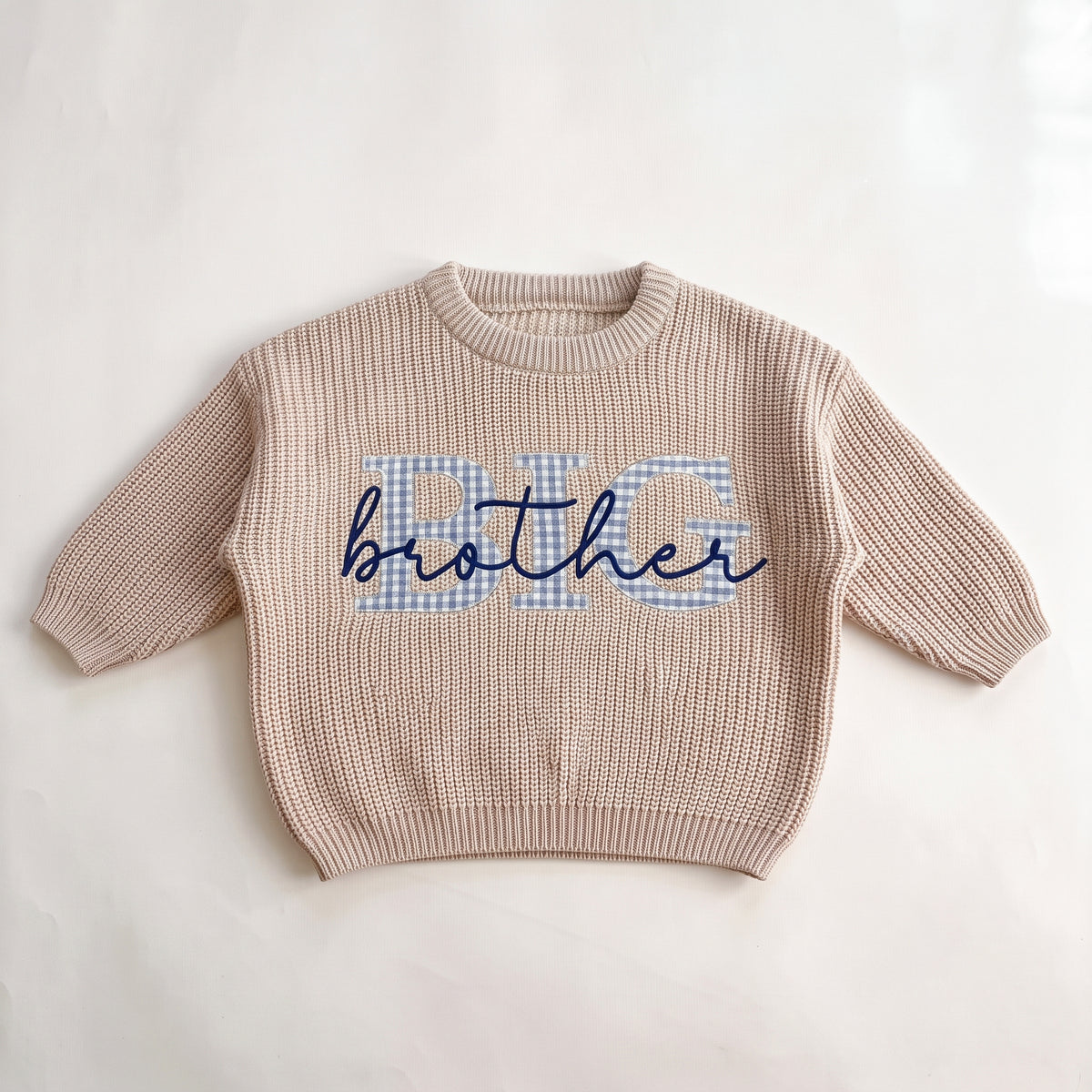 Beige knit sweater with blue gingham BIG applique letters and brother embroidered in navy script, laid flat