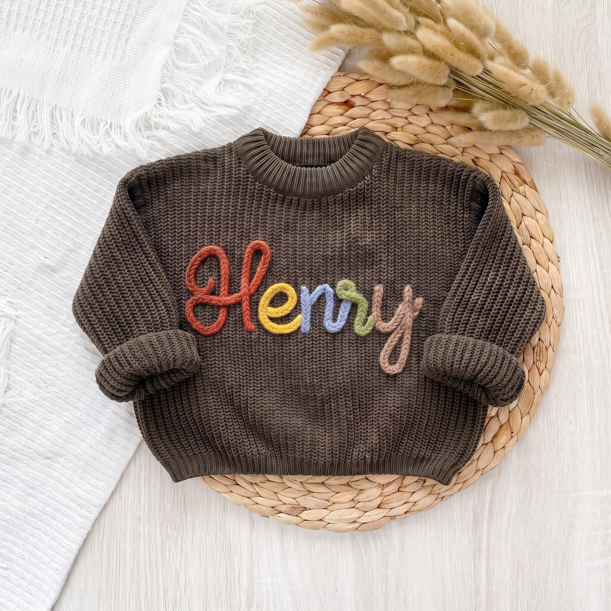 Olive personalized sweater with hand embroidered multicolor yarn name Henry, laid flat