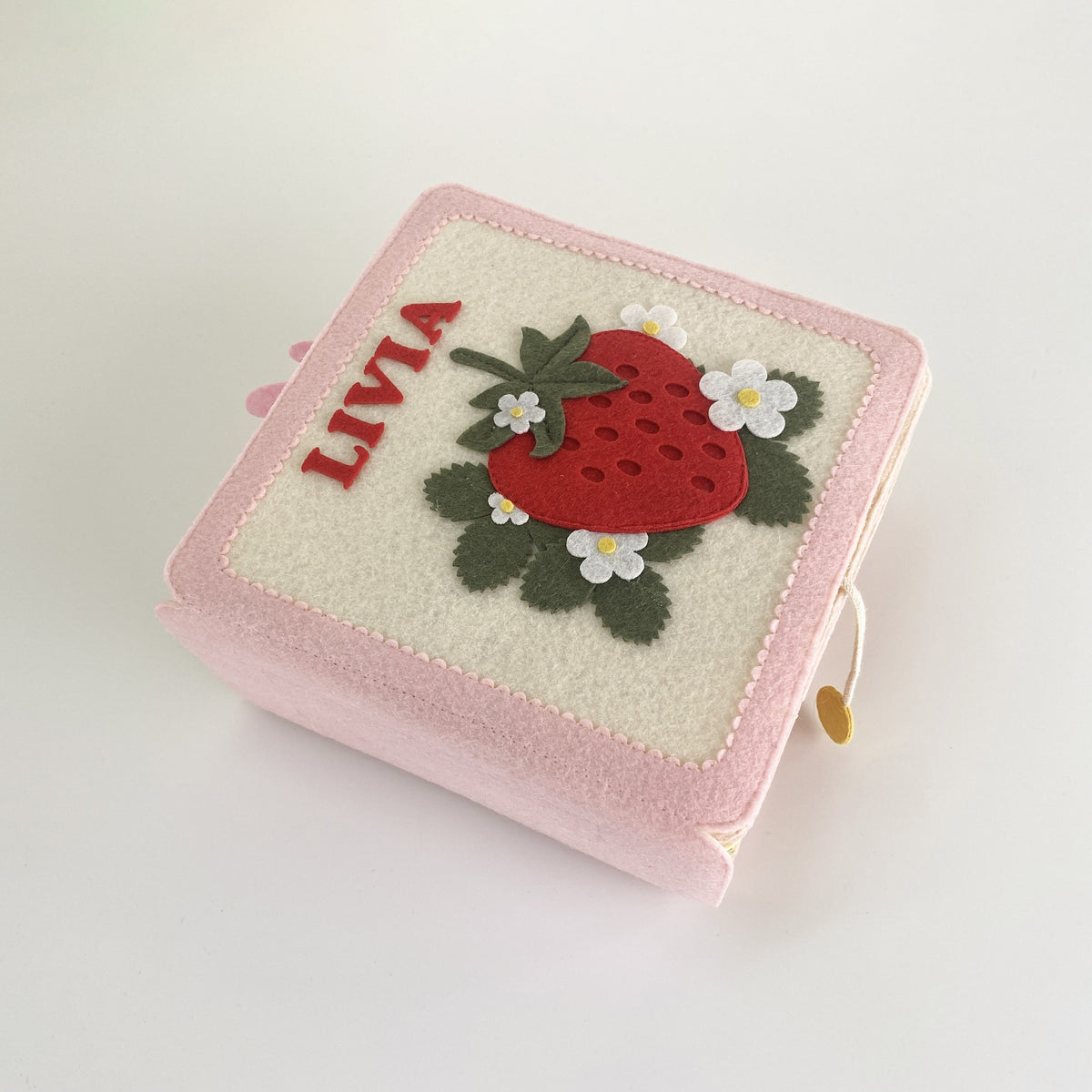 Angled view of a personalized strawberry felt busy book with name Livia