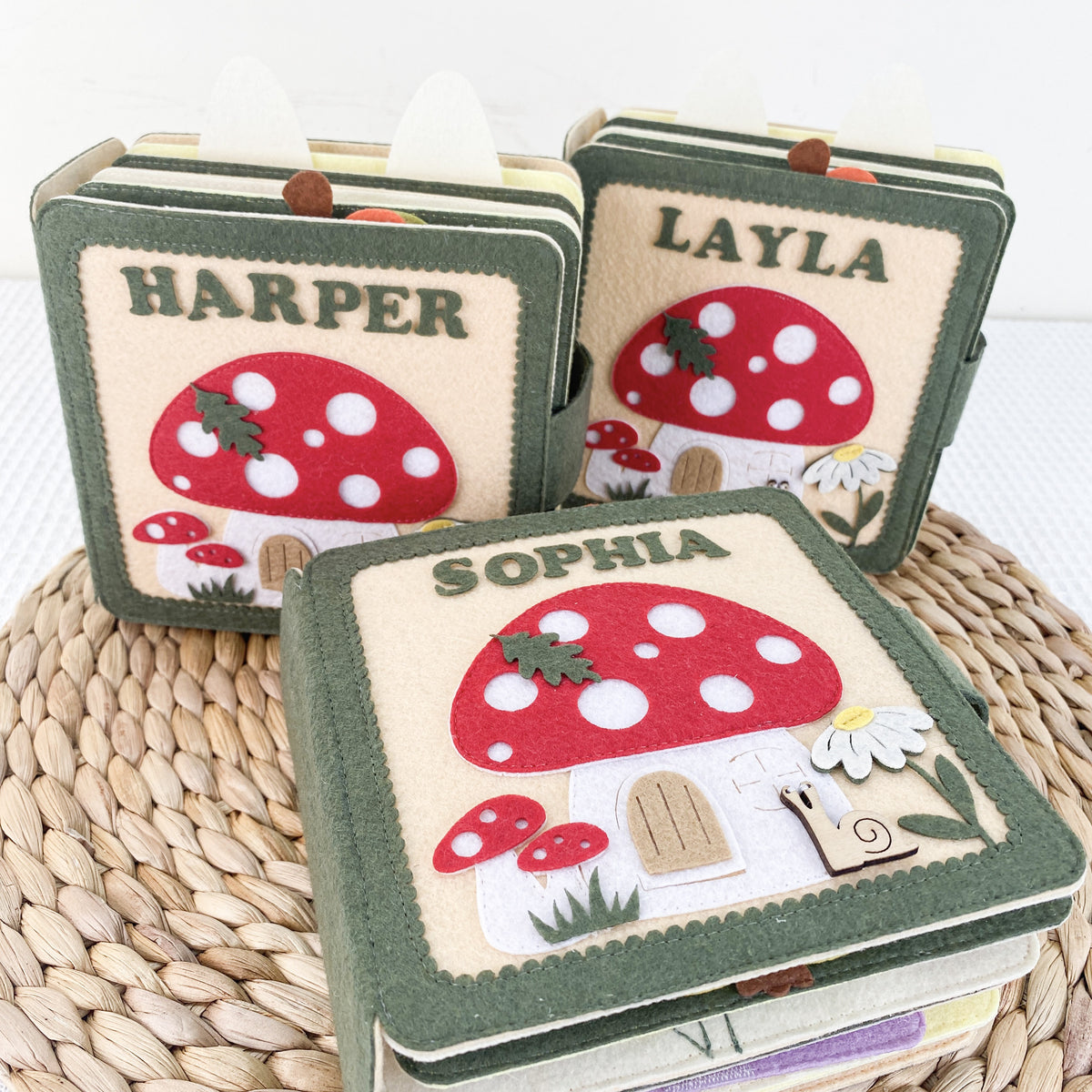 Three personalized mushroom felt busy books with names Harper, Layla and Sophia
