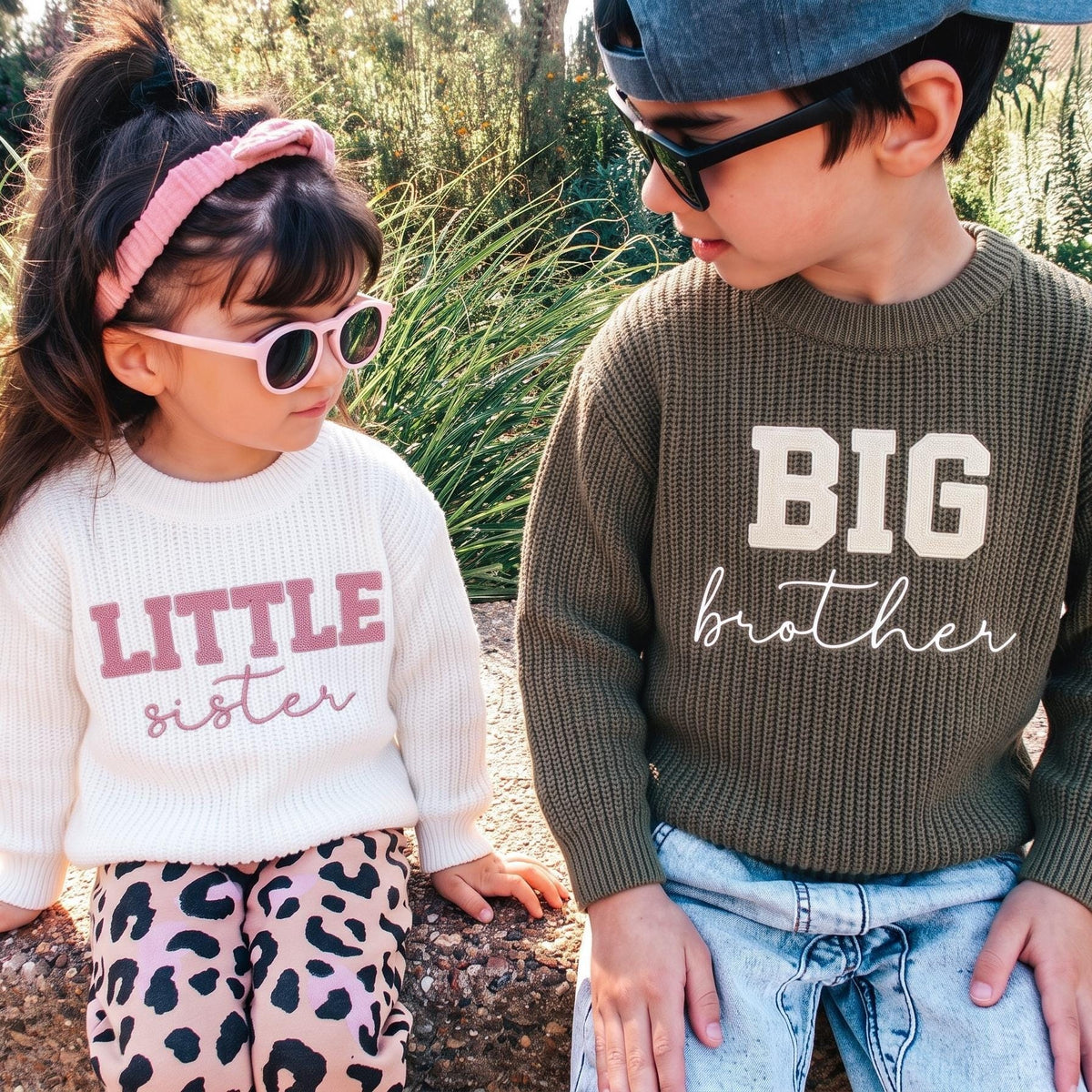 Big brother and little sister wearing matching embroidered sibling sweaters