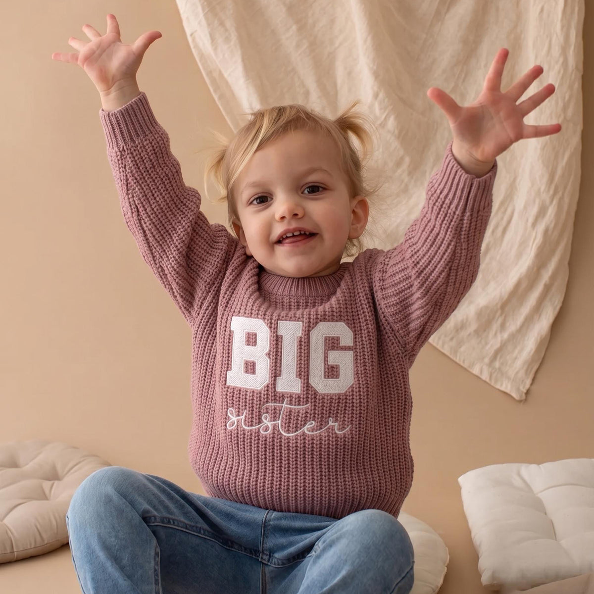 Happy toddler raising arms in pink BIG sister embroidered sweater