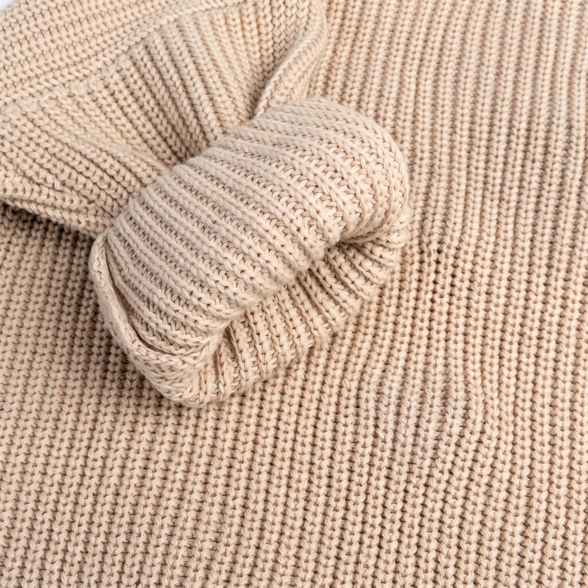 Close-up of the soft cotton knit texture of a beige sweater