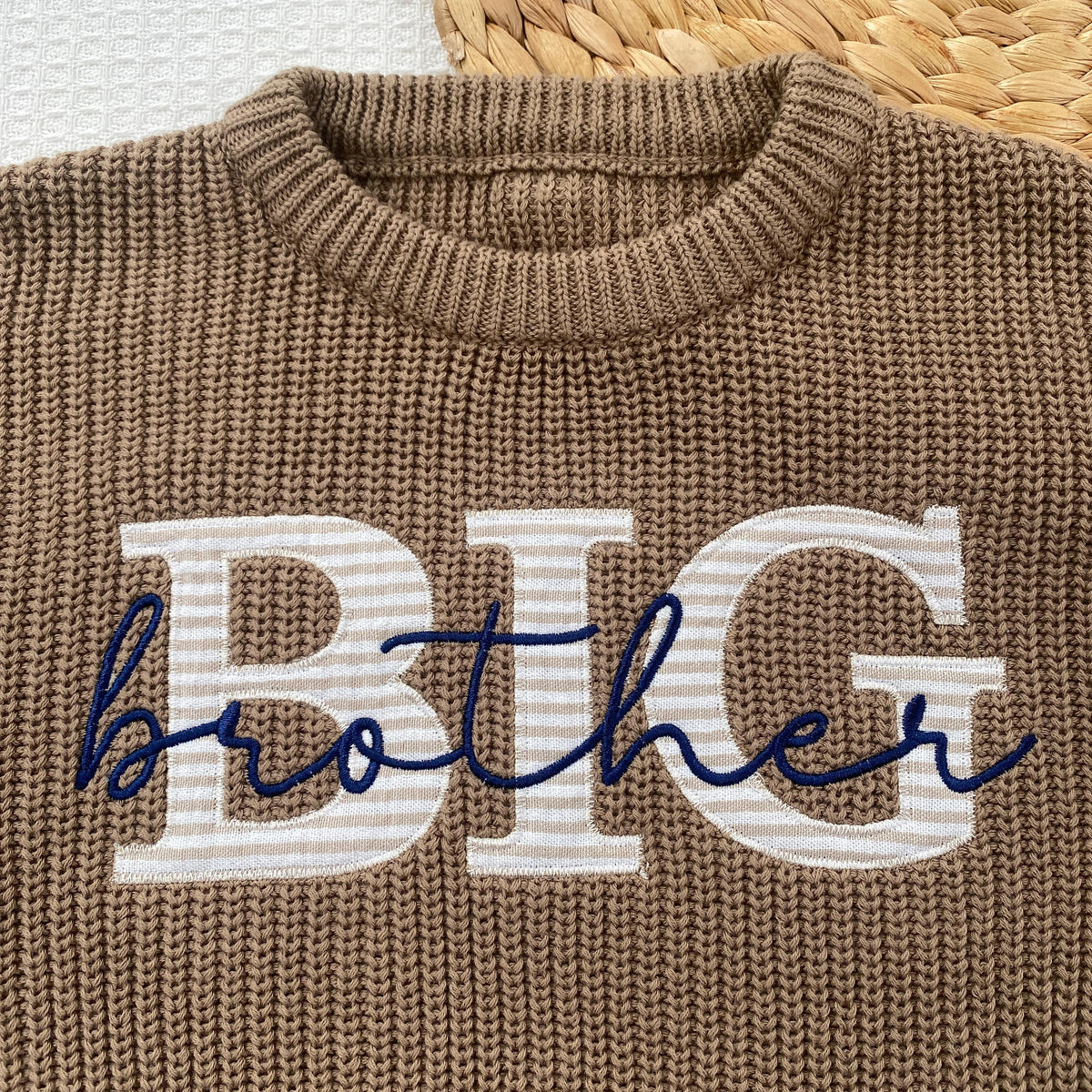 Close-up of BIG fabric applique letters in striped fabric with brother embroidered in navy script on a khaki knit sweater