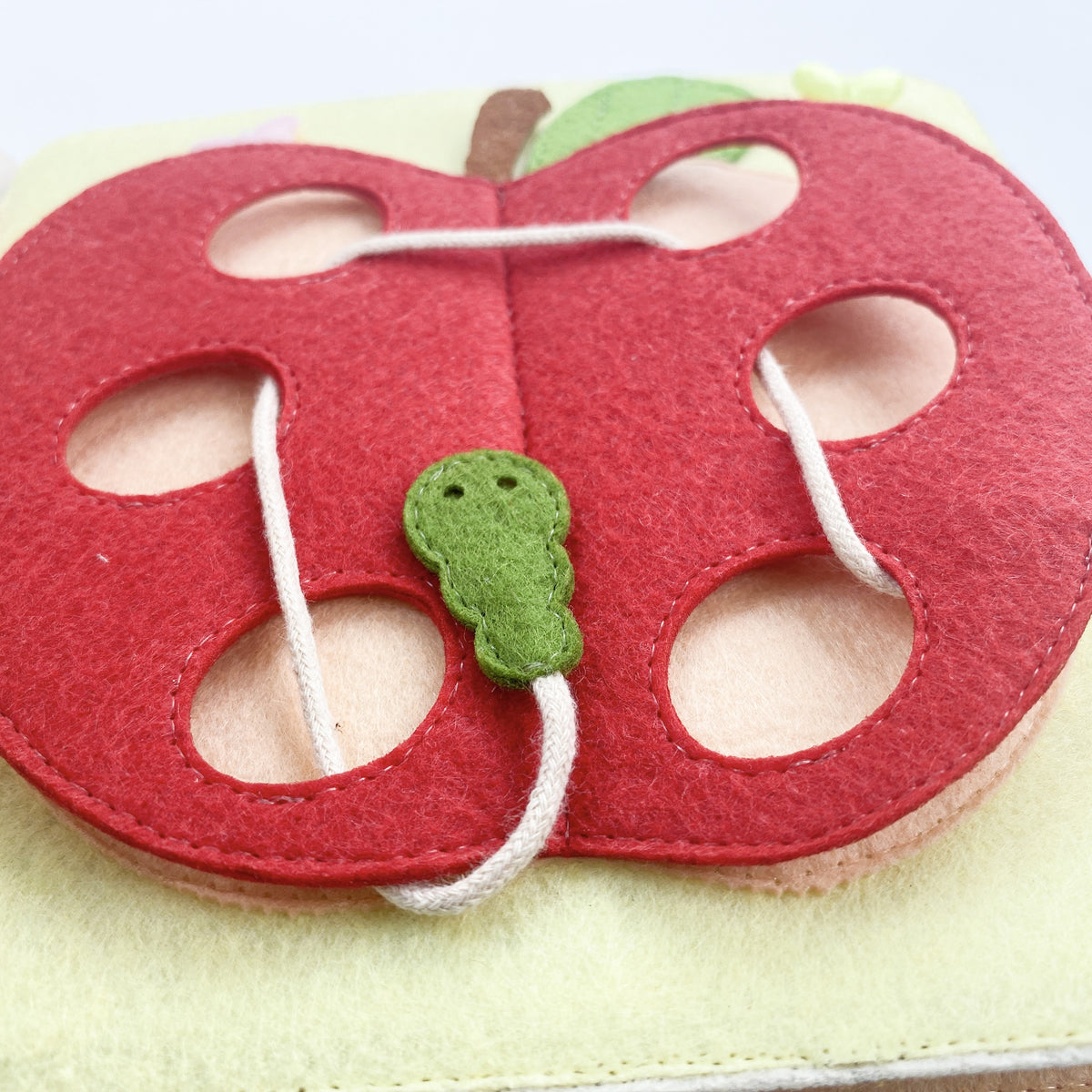 Felt apple threading page with a caterpillar lace in a personalized quiet book