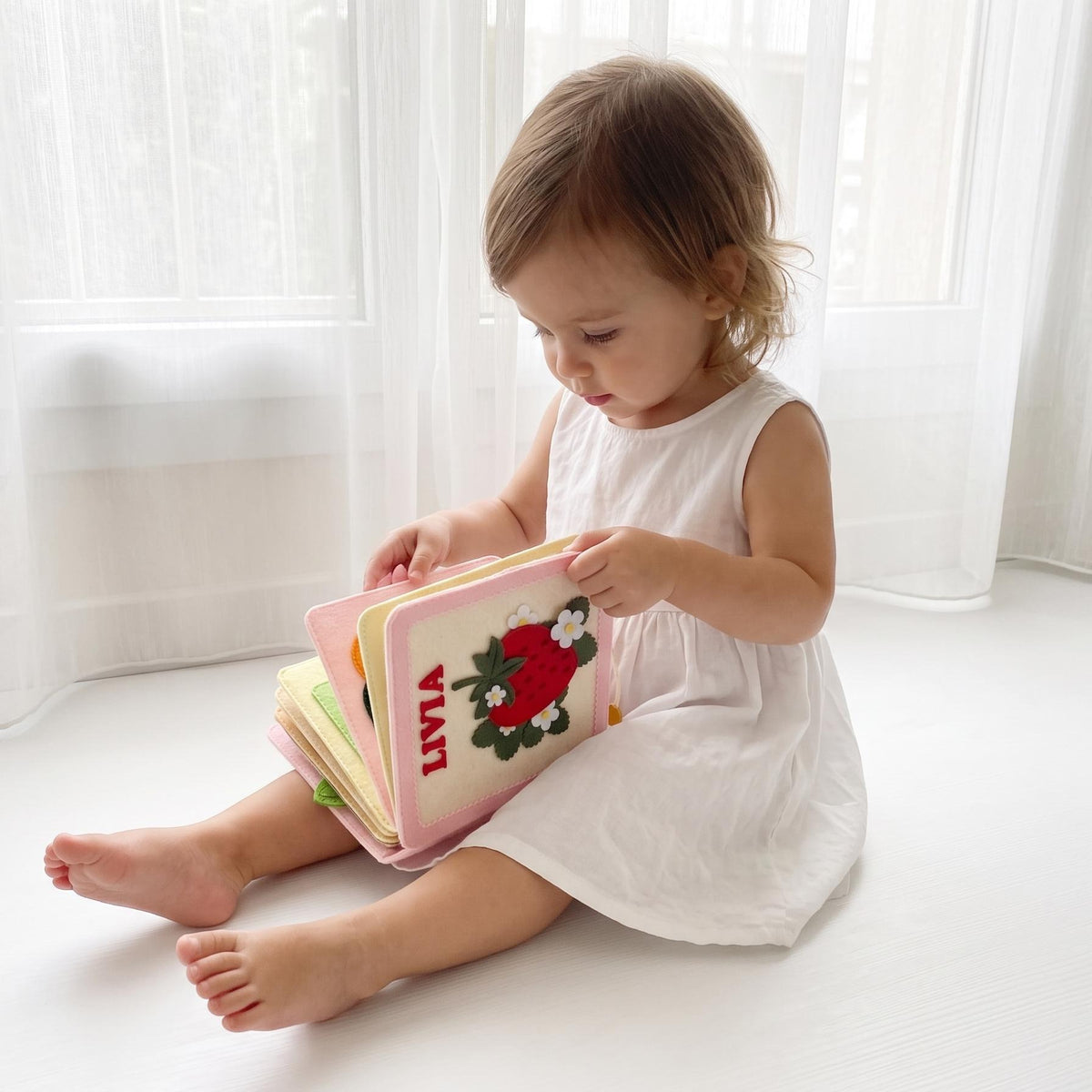 Toddler girl playing with a personalized strawberry felt busy book
