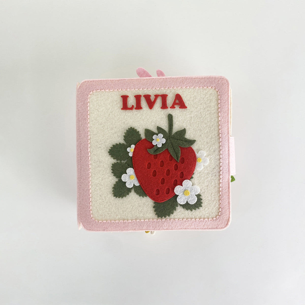 Top view of a personalized strawberry felt busy book with embroidered name Livia