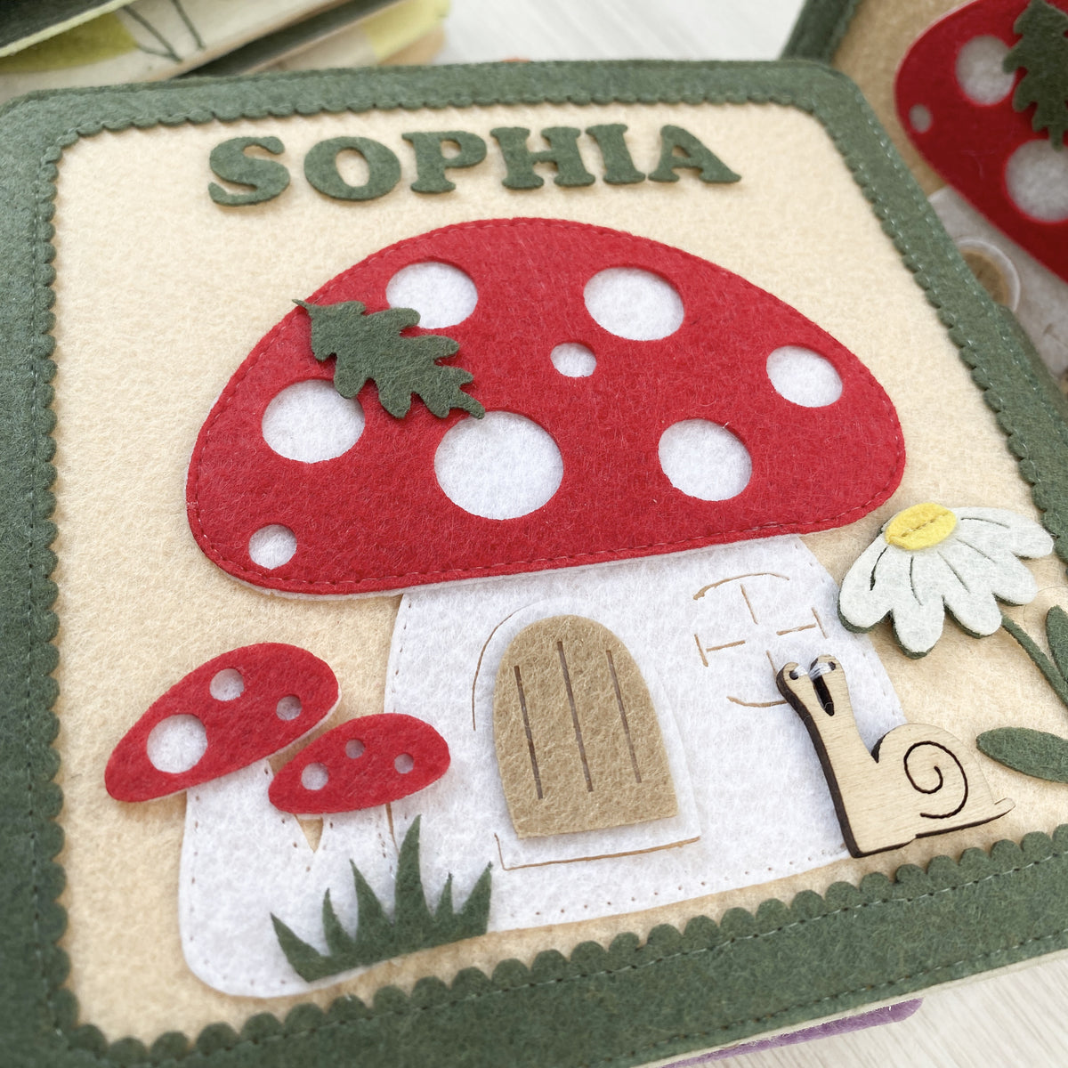 Close-up of embroidered name Sophia on a felt mushroom fairy garden quiet book cover
