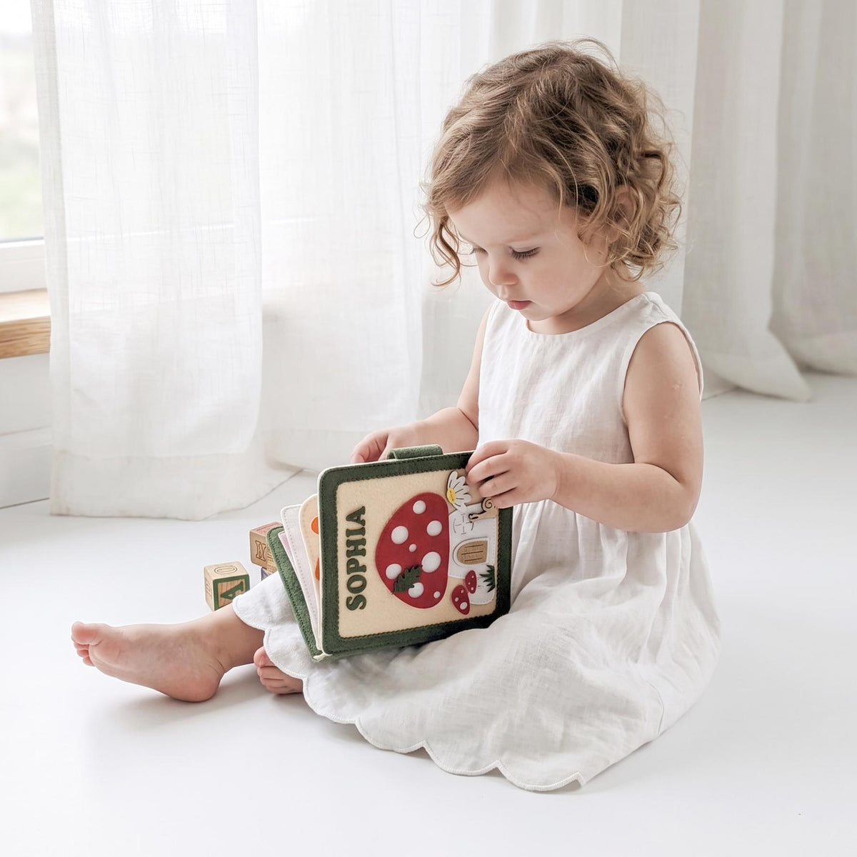 Toddler girl playing with a personalized mushroom felt busy book